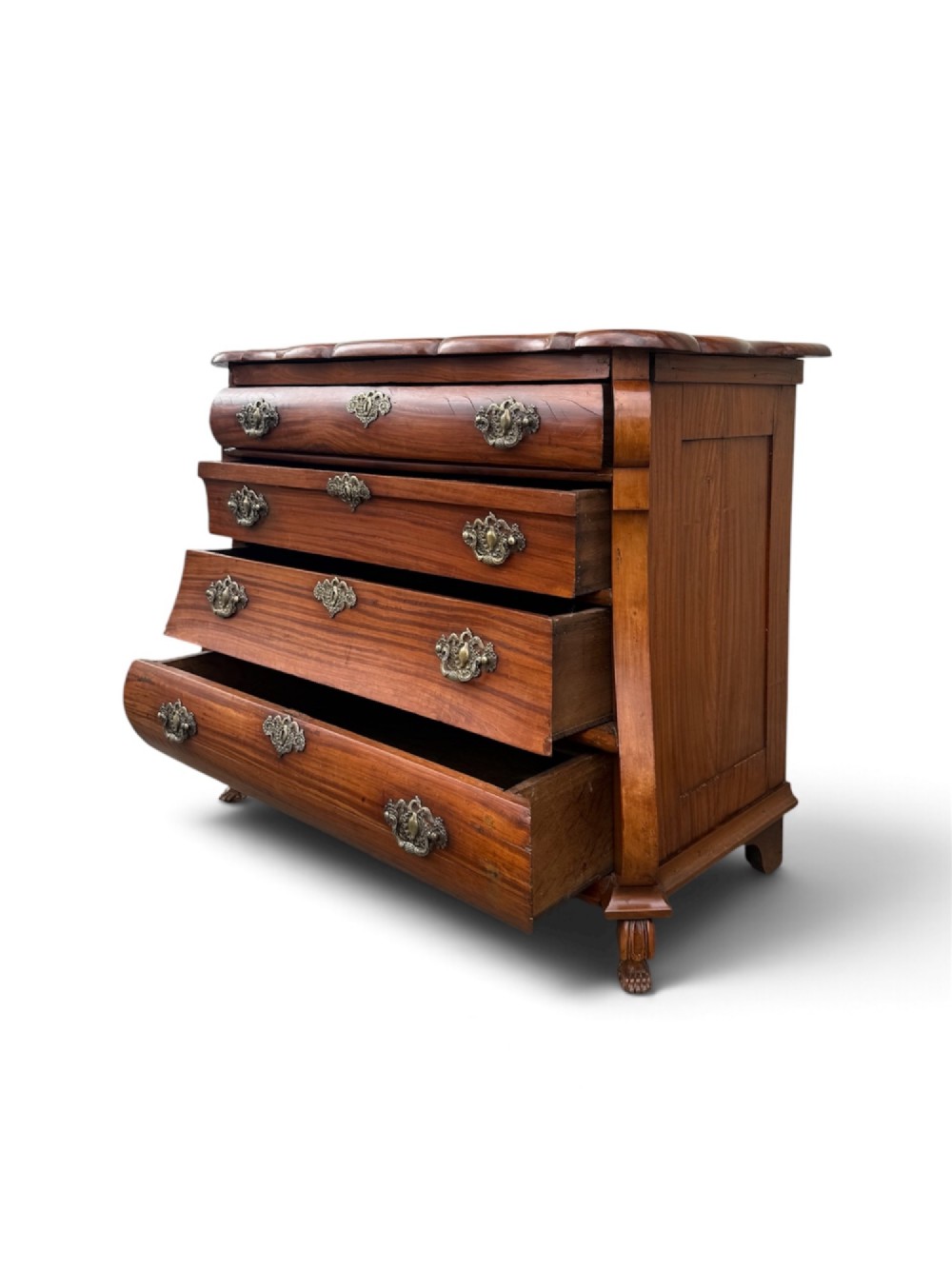 An 18th-century Dutch Colonial solid satinwood bombe chest featuring four graduated drawers, ornate brass handles, and carved feet. View VI
