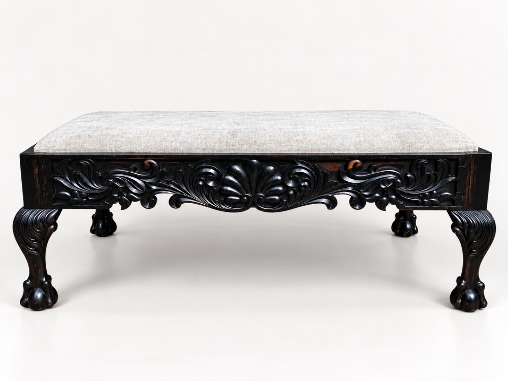 A 19th-century Ceylonese calamander wood stool featuring detailed floral relief carvings on the frame, cabriole legs with claw-and-ball feet, and neutral upholstered seat. View V