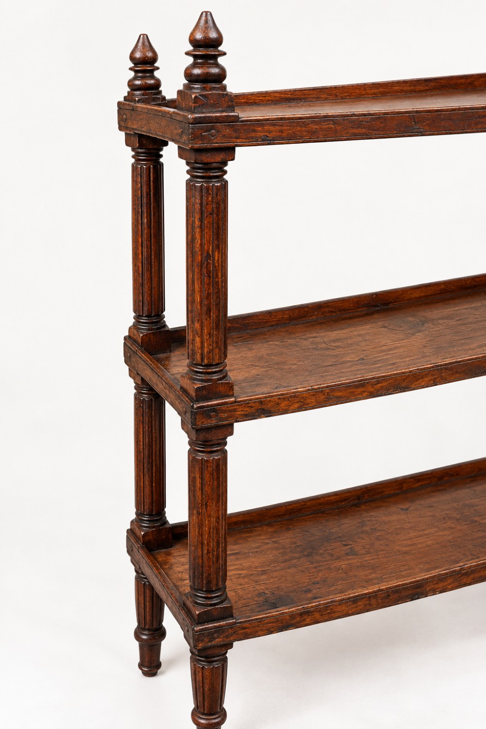 An early 19th-century dark hardwood three-tier open shelving unit featuring fluted vertical columns, turned legs, and carved top finials. View V