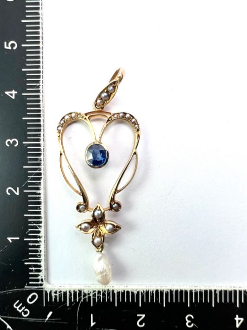fig 1. An Art Nouveau 15ct gold openwork lavalier pendant set with seed pearls, a central oval sapphire, and a hanging baroque pearl drop.
