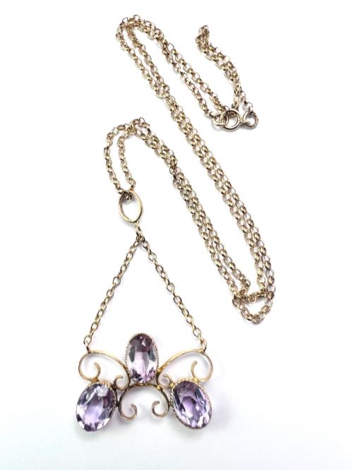 fig 1. An Edwardian 9ct gold pendant necklace featuring three oval facet-cut purple amethysts set within openwork gold scrollwork.