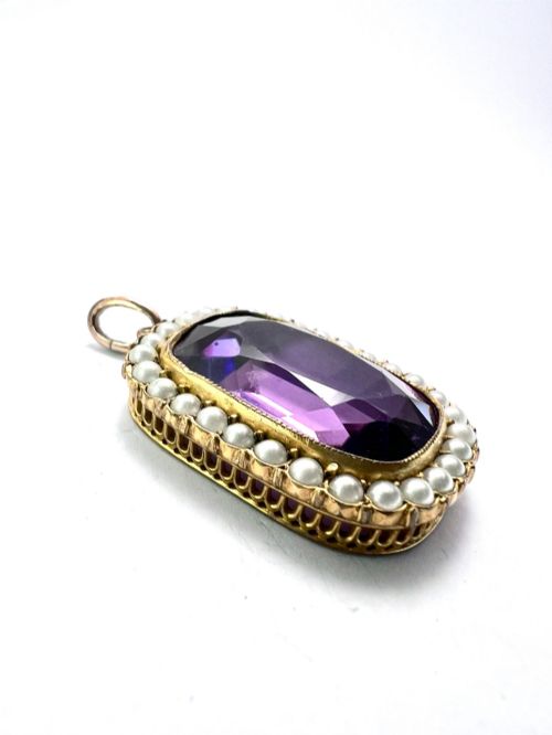 fig 2. A Victorian rectangular cushion-cut purple paste stone pendant surrounded by a halo of small white seed pearls in a gold mount.