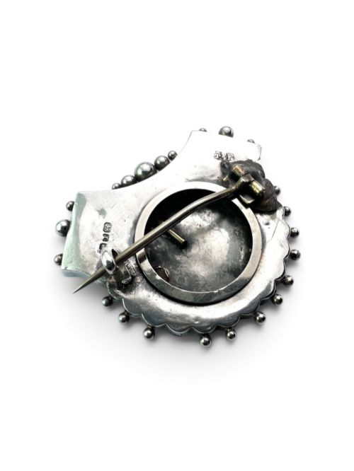 fig 1. A Victorian silver shield-shaped brooch decorated with applied rose gold flowers, hand engraving, and a beaded outer rim.
