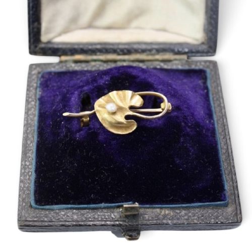 fig 1. An Art Nouveau gold bar brooch shaped as a lily pad leaf holding a central cream pearl.