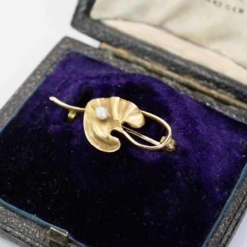 An Art Nouveau gold bar brooch shaped as a lily pad leaf holding a central cream pearl. View IV