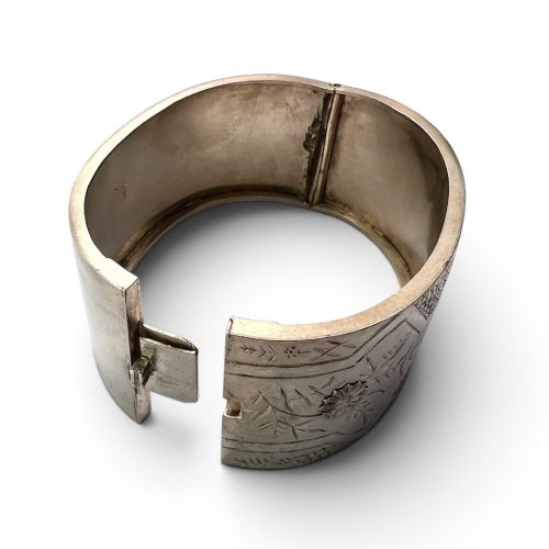 fig 1. A wide Victorian sterling silver hinged cuff bangle featuring hand-engraved floral and geometric patterns across the exterior surface.