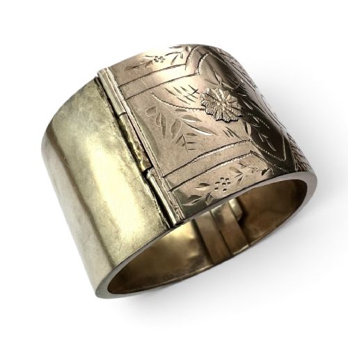 fig 2. A wide Victorian sterling silver hinged cuff bangle featuring hand-engraved floral and geometric patterns across the exterior surface.