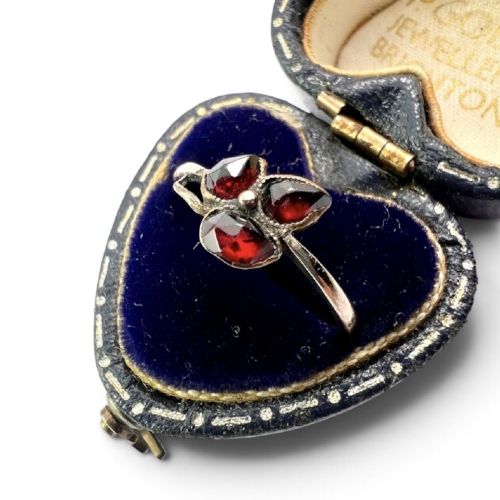 A Victorian 9ct gold ring featuring three deep red garnets arranged in a floral design set upon a slim band. View IV