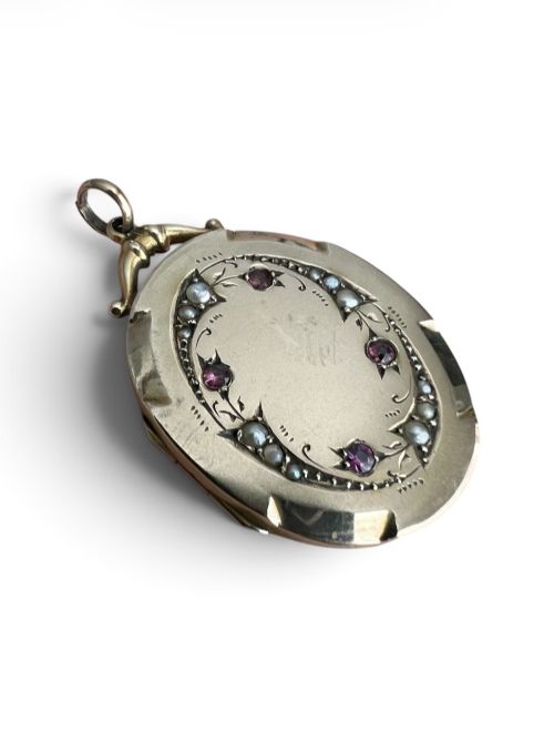fig 1. An oval 9ct yellow gold Victorian locket decorated with foliate engraving and inlaid with rubies and seed pearls.