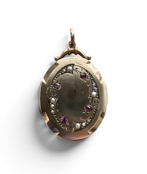 An oval 9ct yellow gold Victorian locket decorated with foliate engraving and inlaid with rubies and seed pearls. View IV