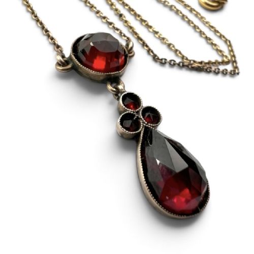 An antique Victorian necklace featuring a fine metal chain holding a drop pendant set with multiple faceted deep red garnets. View III