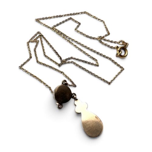An antique Victorian necklace featuring a fine metal chain holding a drop pendant set with multiple faceted deep red garnets. View IV
