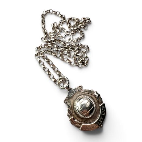 A sterling silver chain necklace featuring a shield-shaped football medal pendant engraved with 1945-6 and JR Fishley Cup. View VII