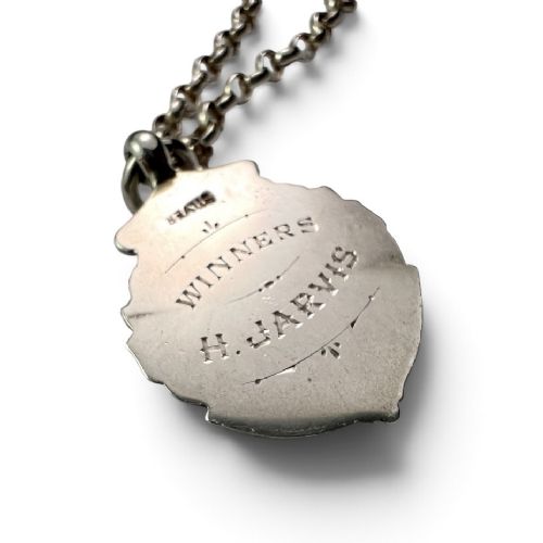 A sterling silver chain necklace featuring a shield-shaped football medal pendant engraved with 1945-6 and JR Fishley Cup. View IX