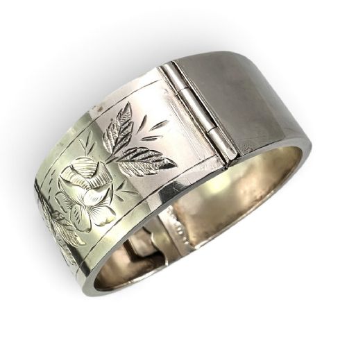 An antique Victorian sterling silver hinged bangle with hand-engraved floral and leaf motifs and interior hallmarks. View III