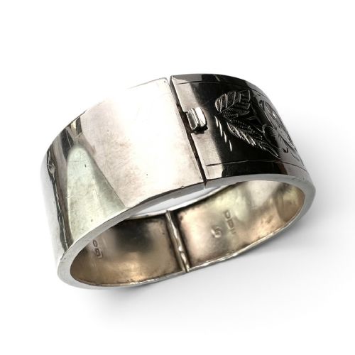 An antique Victorian sterling silver hinged bangle with hand-engraved floral and leaf motifs and interior hallmarks. View IV