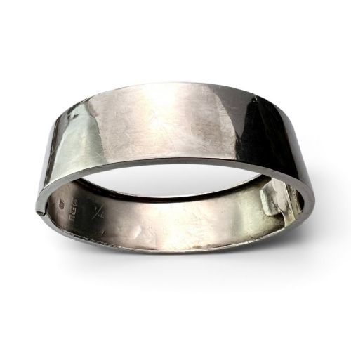 An antique Victorian sterling silver hinged bangle with hand-engraved floral and leaf motifs and interior hallmarks. View V
