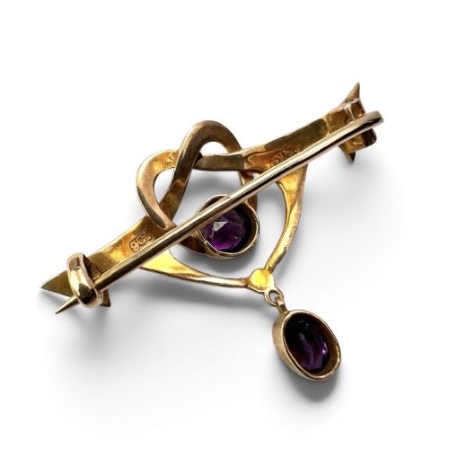An Art Nouveau 9ct gold brooch featuring a heart-shaped whiplash frame set with a round purple amethyst and a suspended amethyst drop, displayed inside a fitted velvet case. View III