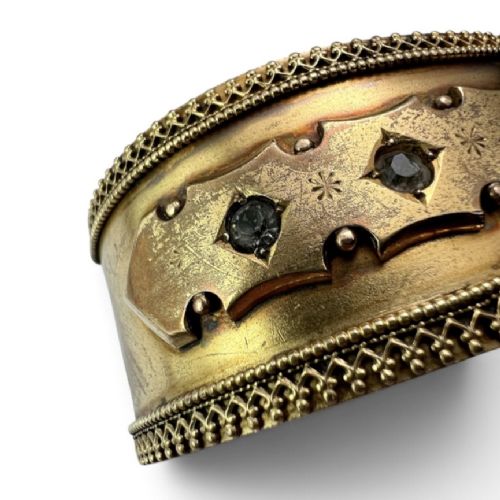 A wide Victorian Etruscan Revival gold hinged bangle decorated with intricate beadwork borders and star-set gemstones across a central band. View IV