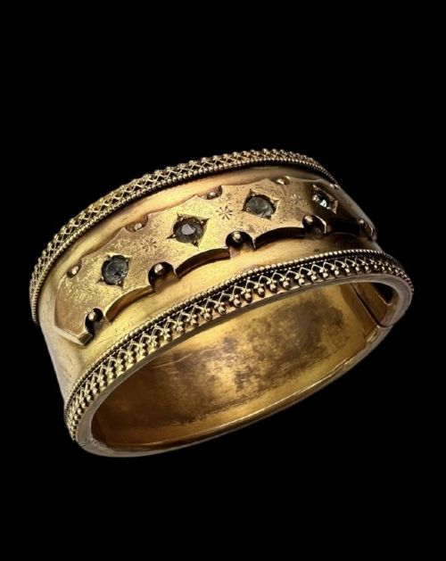 A wide Victorian Etruscan Revival gold hinged bangle decorated with intricate beadwork borders and star-set gemstones across a central band. View VIII