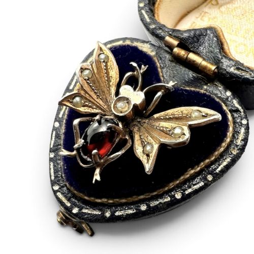 A Victorian silver gilt brooch shaped like an insect, featuring a cabochon red garnet body and wings accented with small seed pearls. View III