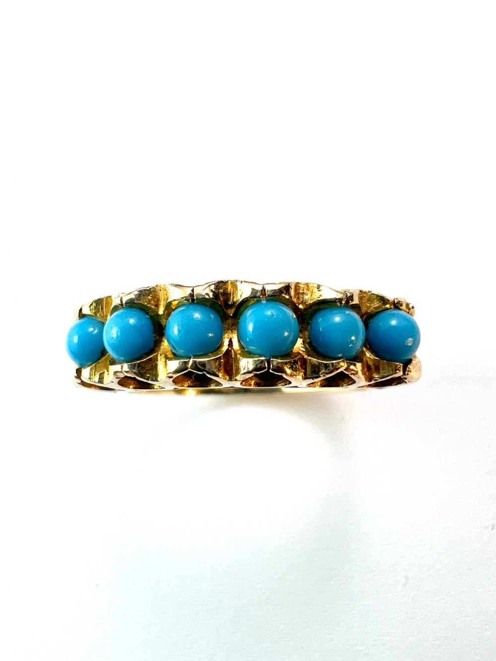 An 18ct yellow gold modernist ring set with six round turquoise cabochons within a textured openwork gallery. View VI