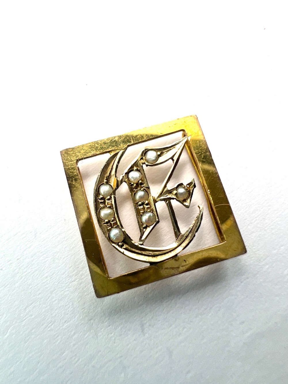 A square 9ct yellow gold Victorian ribbon slider pendant featuring a gothic letter E set with seed pearls. View II