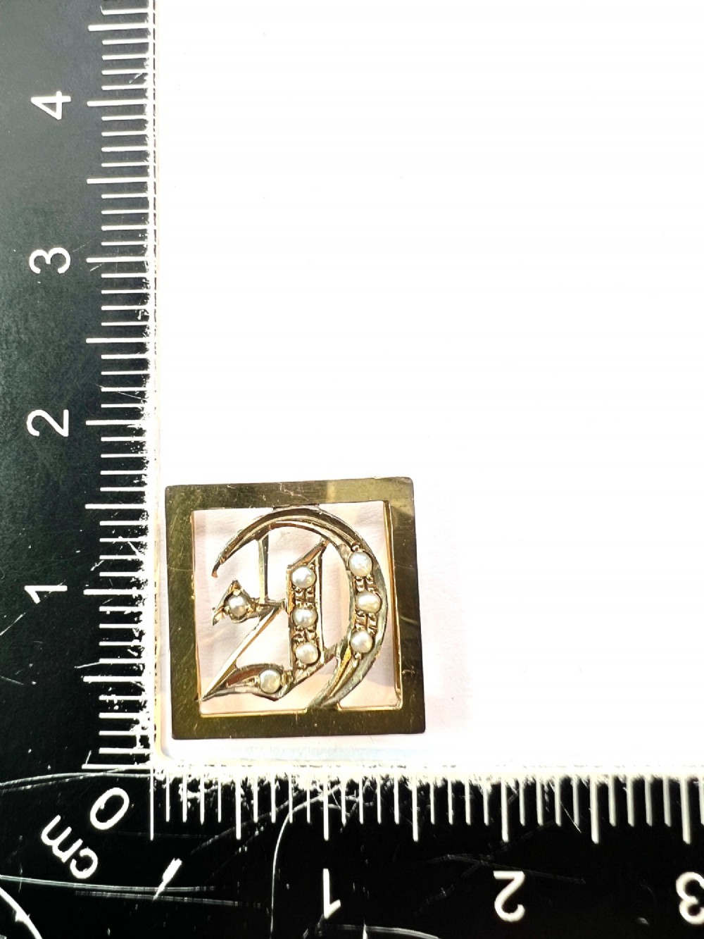 A square 9ct yellow gold Victorian ribbon slider pendant featuring a gothic letter E set with seed pearls. View IX