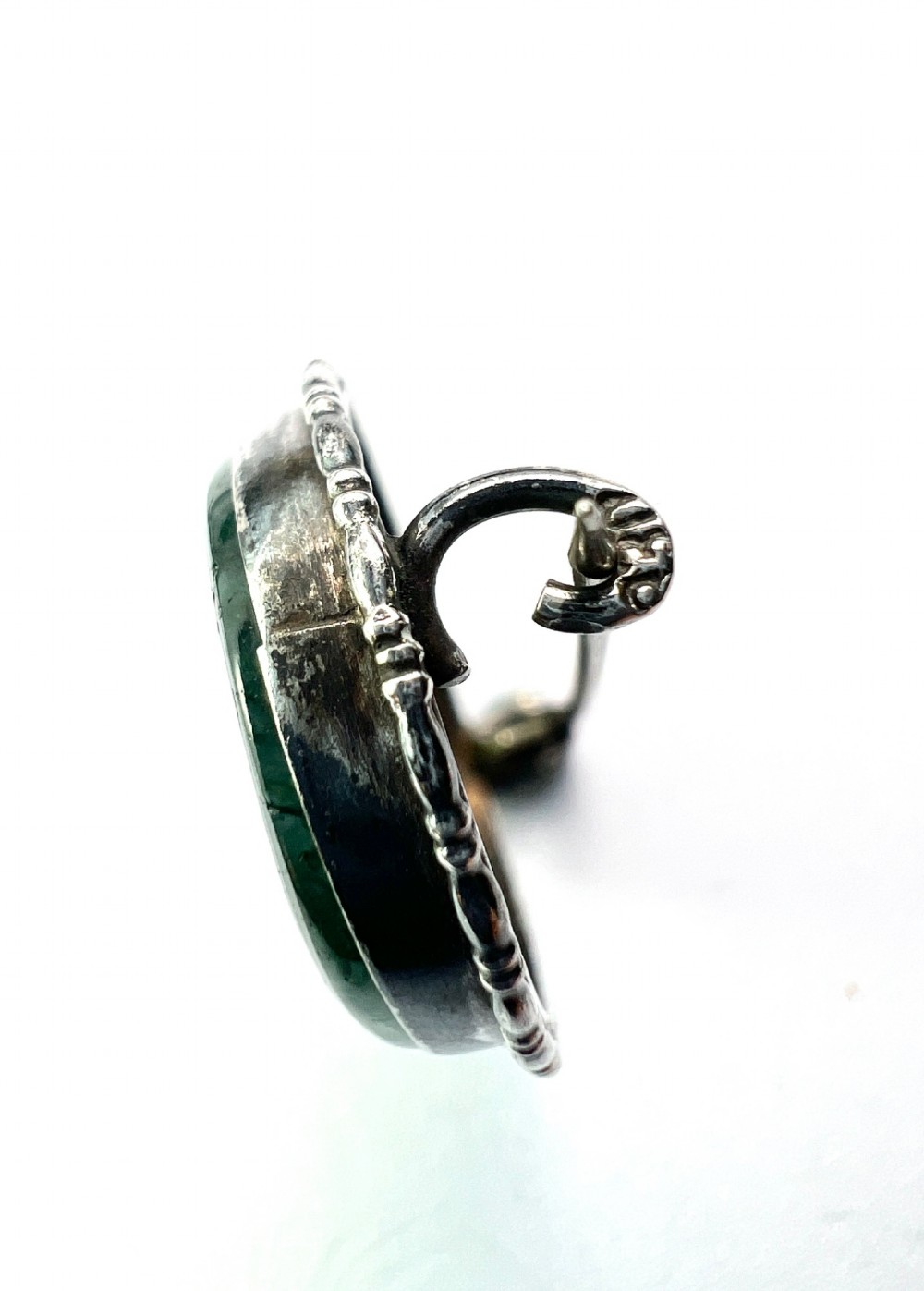 An oval antique sterling silver brooch featuring a translucent moss agate cabochon with green dendritic inclusions within an engraved bezel frame. View V