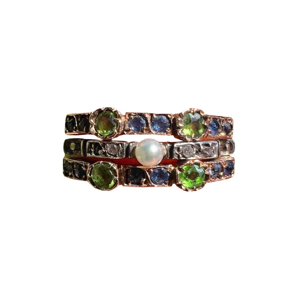 An Edwardian multi-band harem ring crafted in gold and silver, set with green and blue gemstones, diamonds, and a central pearl.