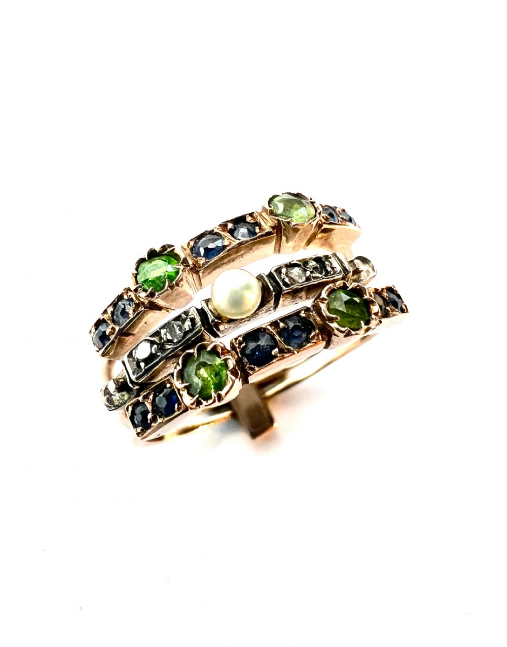 An Edwardian multi-band harem ring crafted in gold and silver, set with green and blue gemstones, diamonds, and a central pearl. View VII