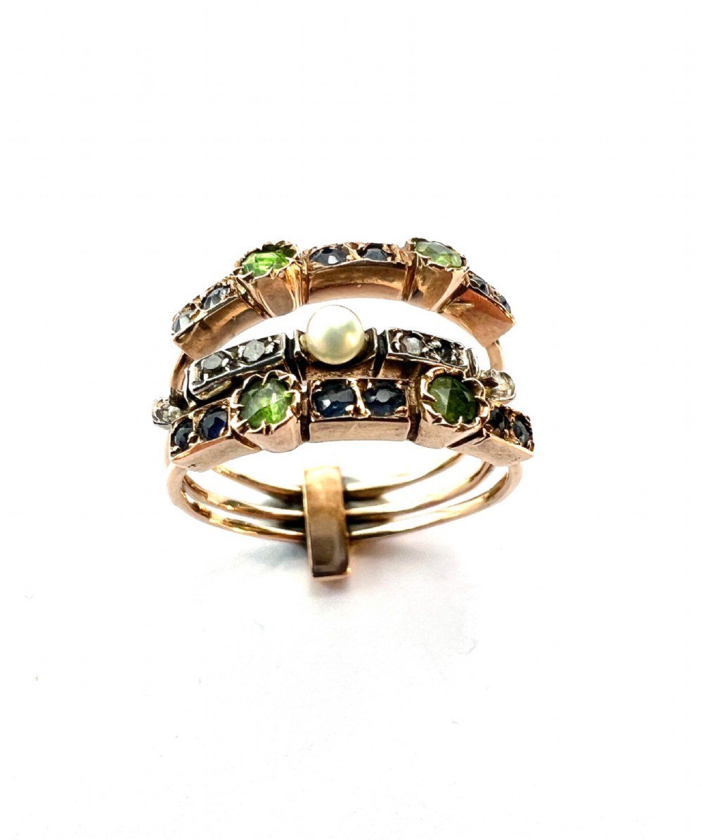 An Edwardian multi-band harem ring crafted in gold and silver, set with green and blue gemstones, diamonds, and a central pearl. View VIII