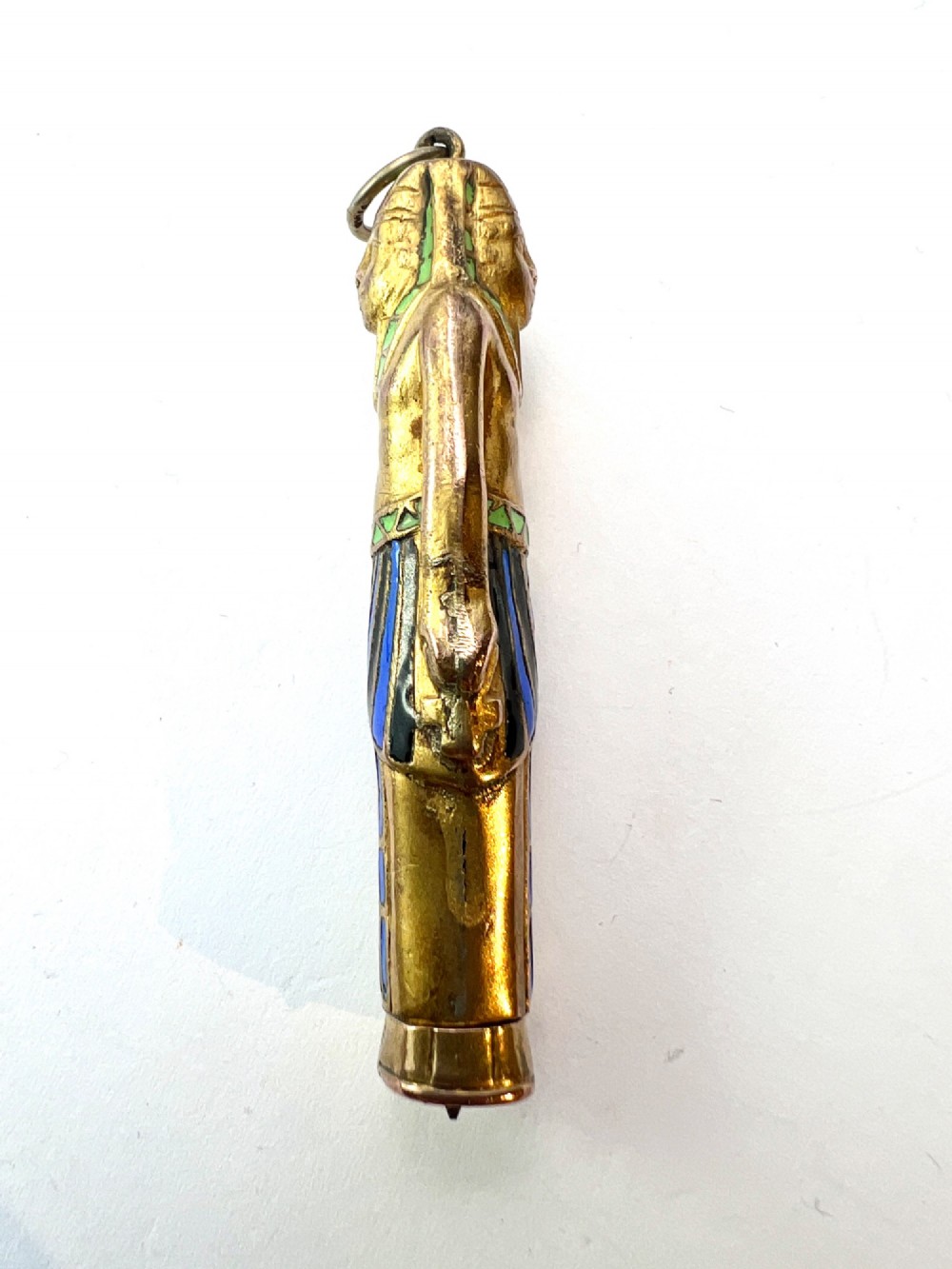 An antique gilt metal and enamel Egyptian Revival sarcophagus pendant featuring a pharaoh figure with blue and green enamelled detailing, designed as a mechanical propelling pencil. View VI