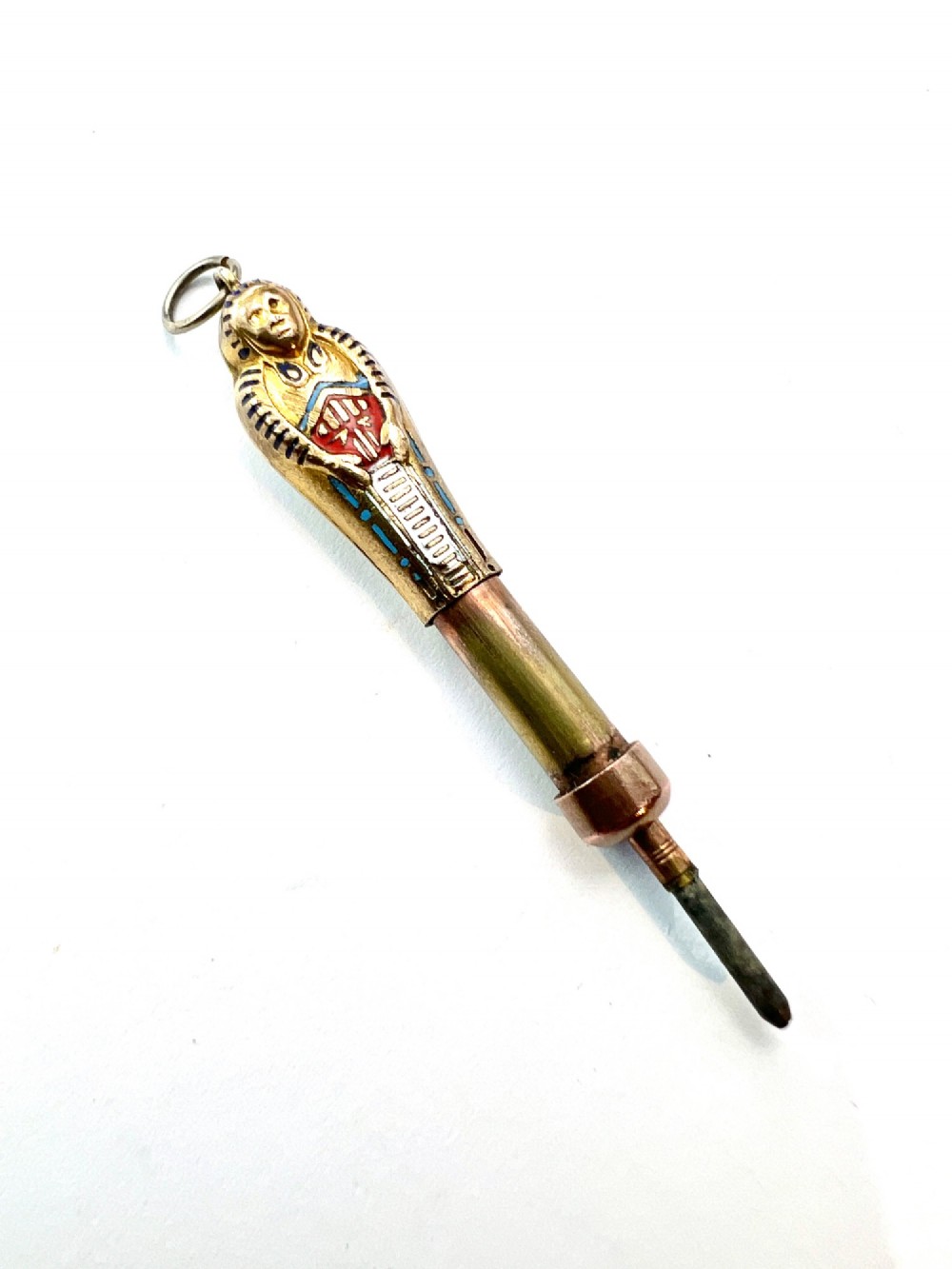 An antique gilt metal sarcophagus-shaped propelling pencil pendant featuring colourful blue, red, and white enamel decoration with a top jump ring. View III