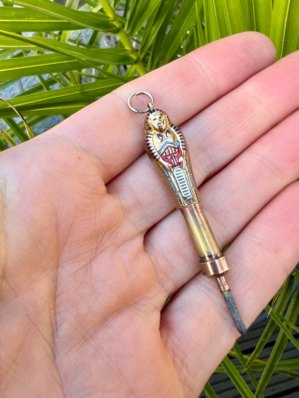 An antique gilt metal sarcophagus-shaped propelling pencil pendant featuring colourful blue, red, and white enamel decoration with a top jump ring. View IX