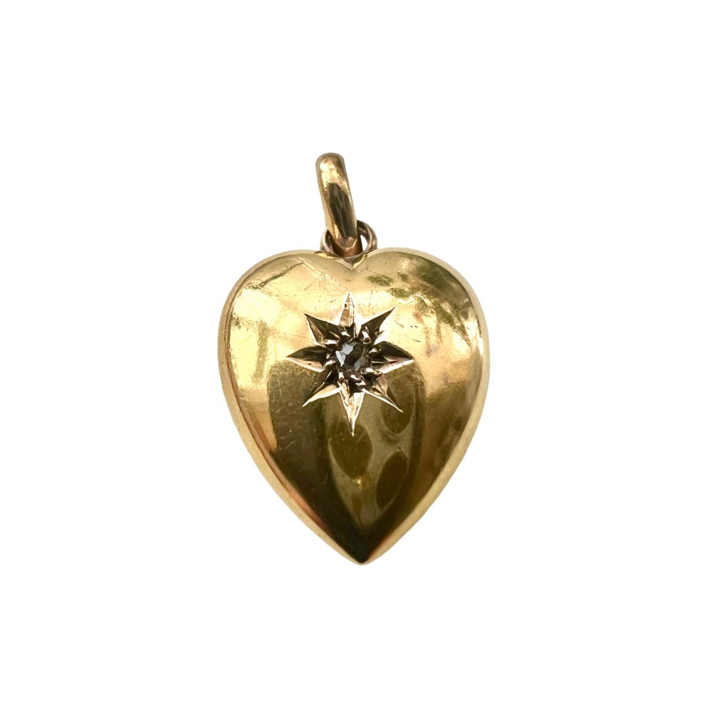 A late Victorian 15ct yellow gold puffed heart pendant featuring a central starburst engraving inset with a small diamond.