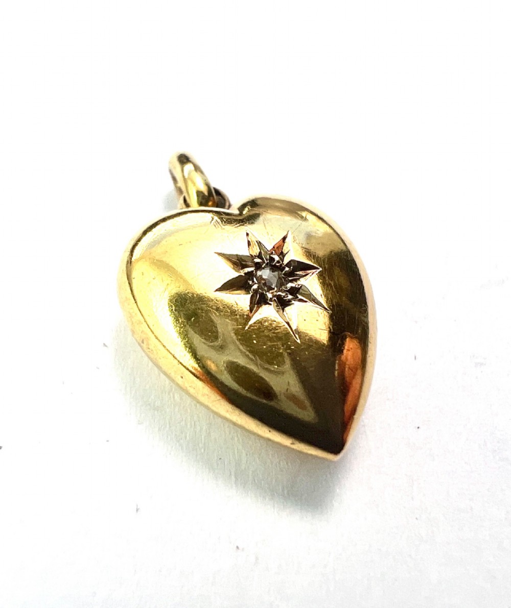 A late Victorian 15ct yellow gold puffed heart pendant featuring a central starburst engraving inset with a small diamond. View II