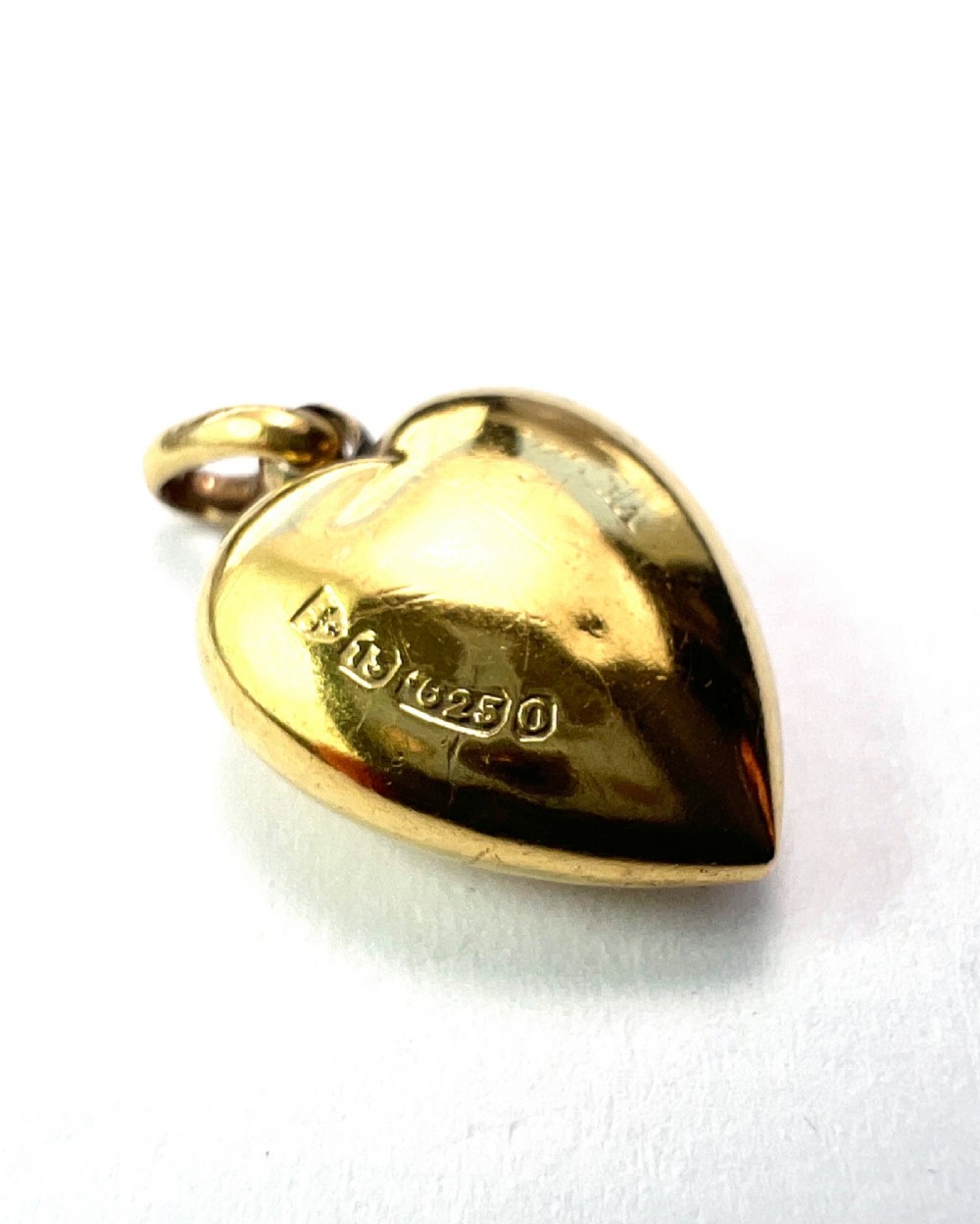 A late Victorian 15ct yellow gold puffed heart pendant featuring a central starburst engraving inset with a small diamond. View IV