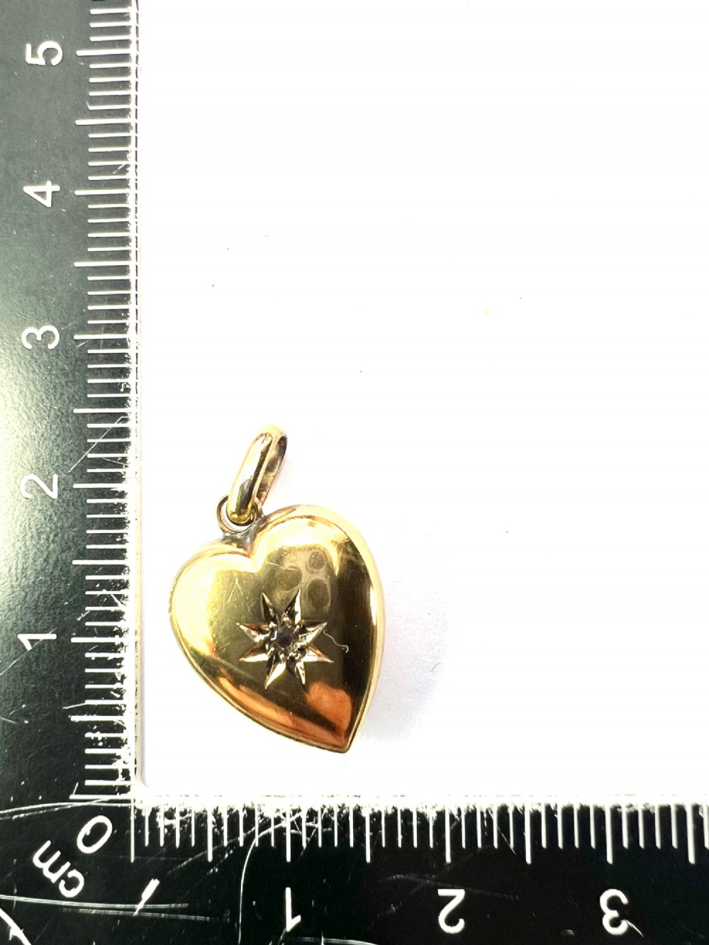 A late Victorian 15ct yellow gold puffed heart pendant featuring a central starburst engraving inset with a small diamond. View VI