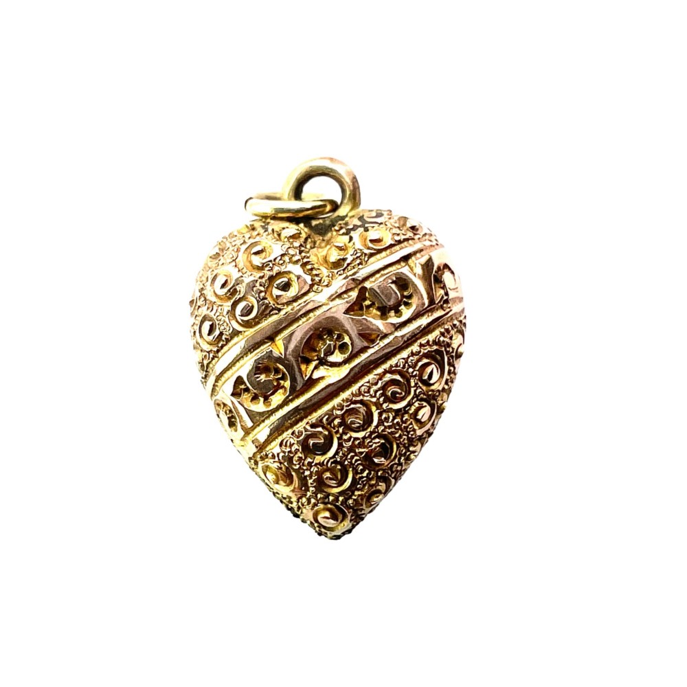 A three-dimensional 9ct gold Victorian heart pendant featuring intricate chased scrollwork and a top suspension ring.