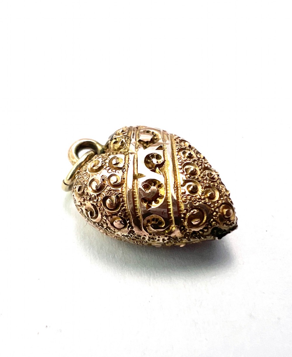 A three-dimensional 9ct gold Victorian heart pendant featuring intricate chased scrollwork and a top suspension ring. View II