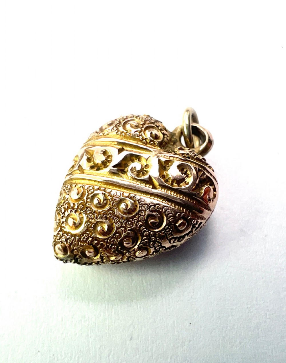 A three-dimensional 9ct gold Victorian heart pendant featuring intricate chased scrollwork and a top suspension ring. View III