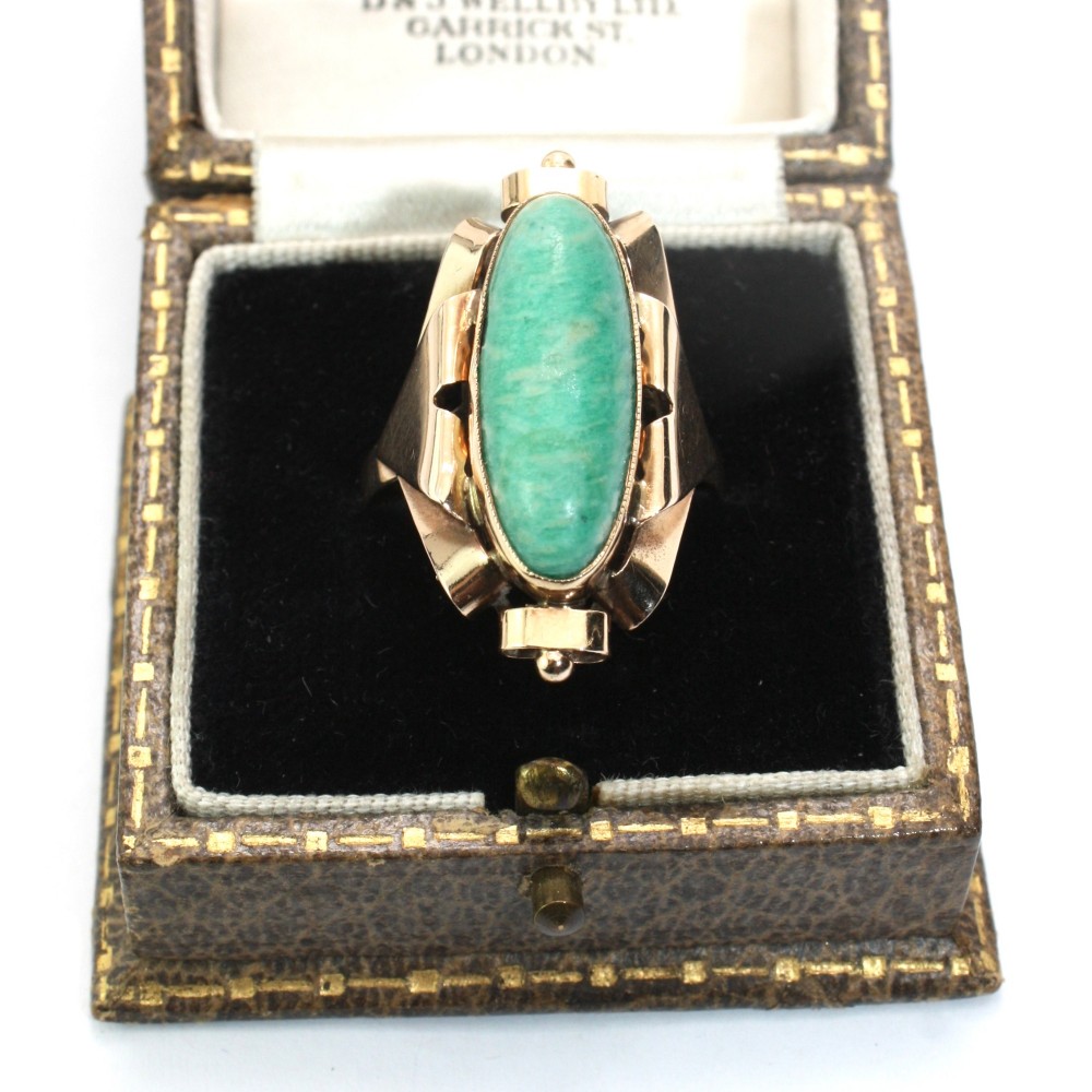 A 1940s gold cocktail ring featuring an elongated green aventurine cabochon set within sculptural scrolled side accents. View II