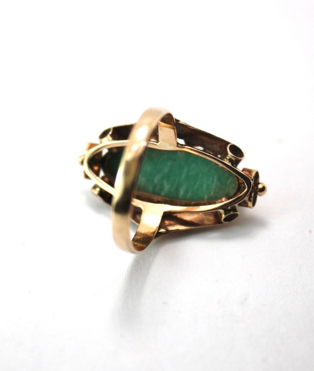 A 1940s gold cocktail ring featuring an elongated green aventurine cabochon set within sculptural scrolled side accents. View V