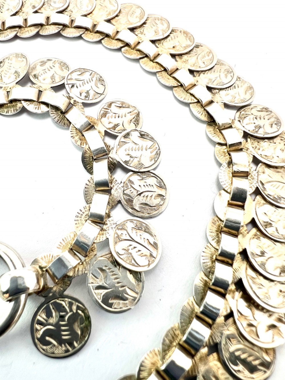 A coiled Victorian sterling silver chain decorated with overlapping, hand-engraved circular coin discs and secured with a traditional bolt ring clasp. View IV