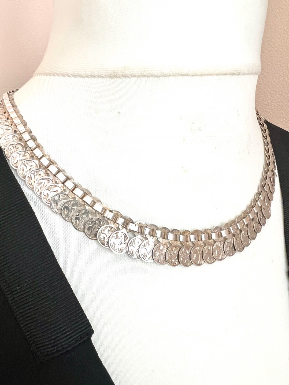 A coiled Victorian sterling silver chain decorated with overlapping, hand-engraved circular coin discs and secured with a traditional bolt ring clasp. View IX