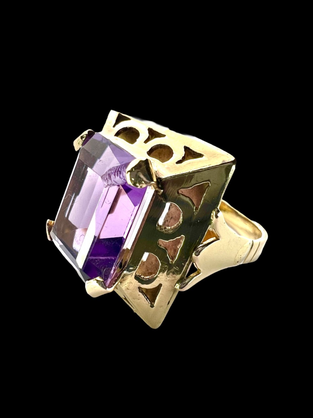A vintage 14-carat yellow gold cocktail ring featuring a rectangular emerald-cut amethyst set in a raised geometric openwork gallery. View II
