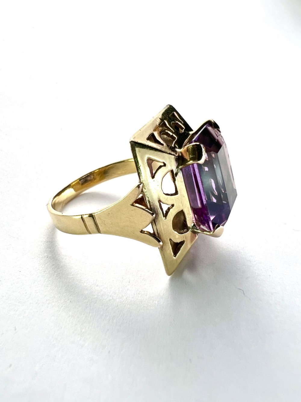A vintage 14-carat yellow gold cocktail ring featuring a rectangular emerald-cut amethyst set in a raised geometric openwork gallery. View IV