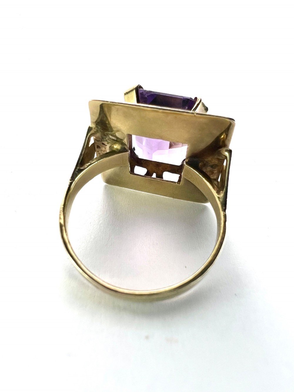 A vintage 14-carat yellow gold cocktail ring featuring a rectangular emerald-cut amethyst set in a raised geometric openwork gallery. View V