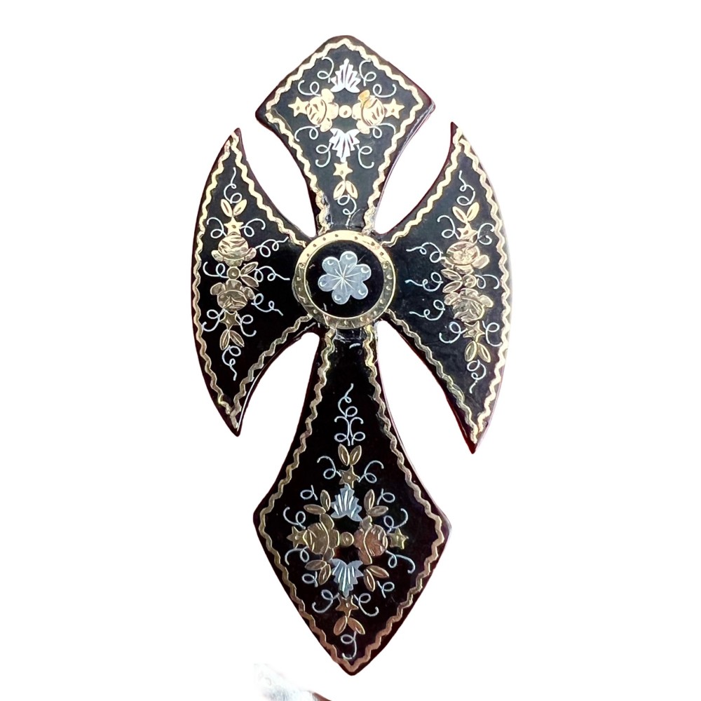 A Victorian cross brooch crafted from dark tortoiseshell with gold and silver pique floral inlays.